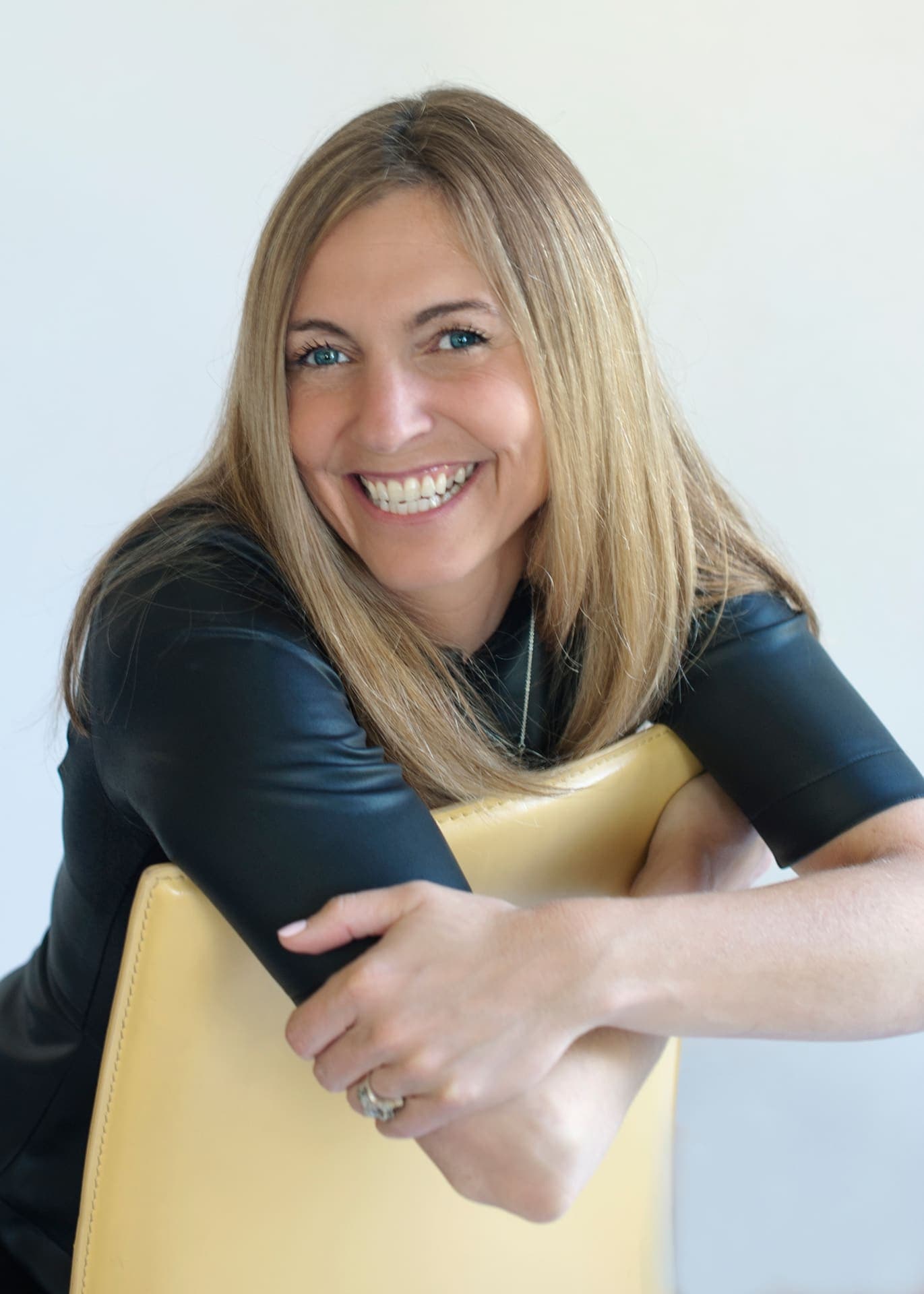 Portrait of a smiling Level Up facilitator leaning on a chair.