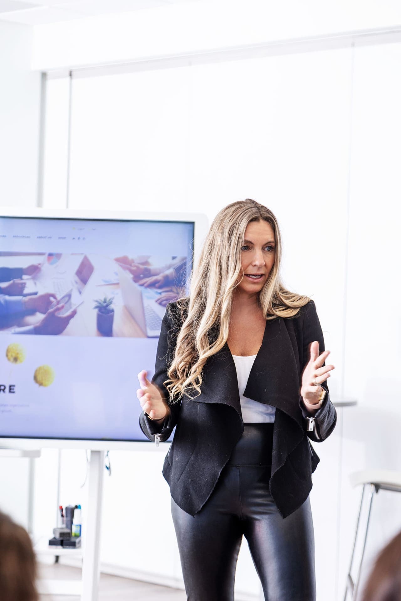 A facilitator presenting beside a screen to a room of participants.