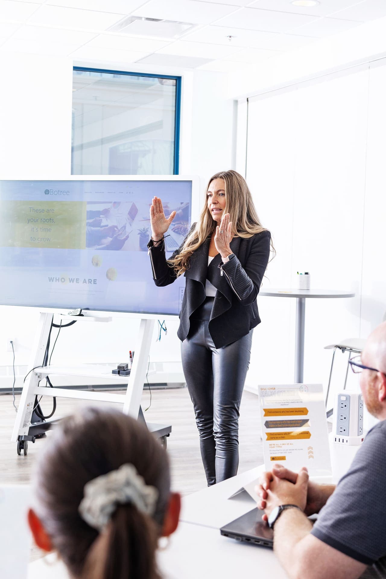 A facilitator presenting to leaders seated around a workshop table.
