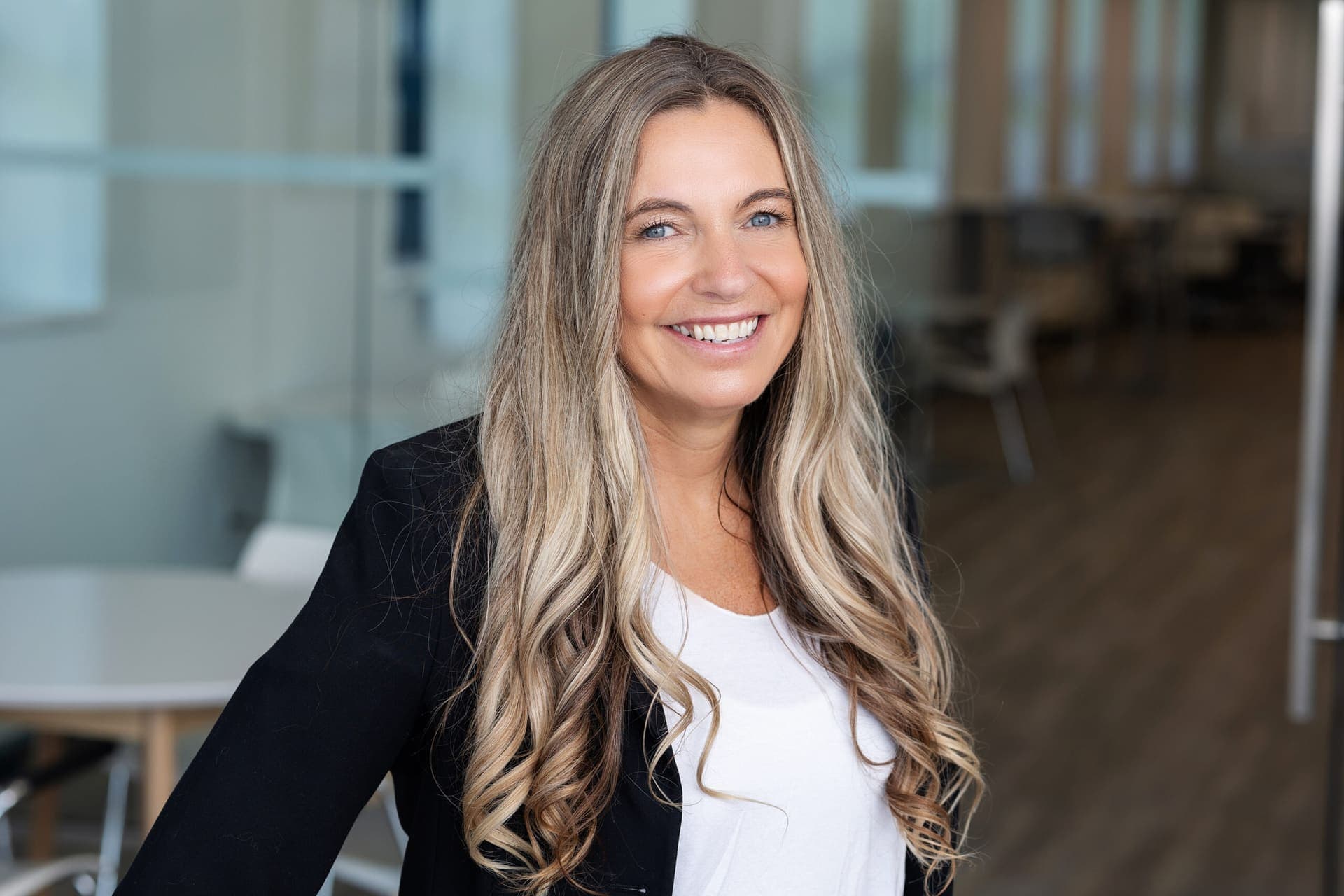 A smiling Level Up facilitator in a black blazer in a modern office.