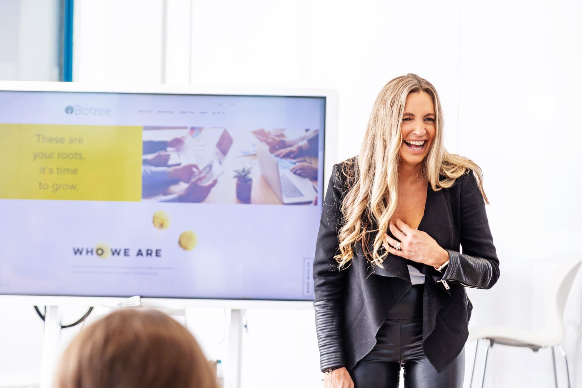 A facilitator laughing in front of a presentation slide titled Who We Are.